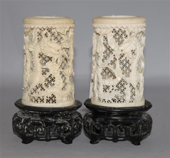 A pair of Chinese carved ivory tusk reticulated vases, carved with dragons among clouds and with carved and pierced hardwood stands